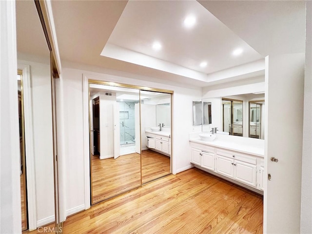 bathroom featuring hardwood / wood-style flooring, vanity, and a tray ceiling