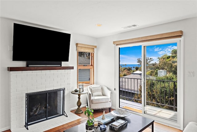 living room featuring a brick fireplace and light hardwood / wood-style flooring