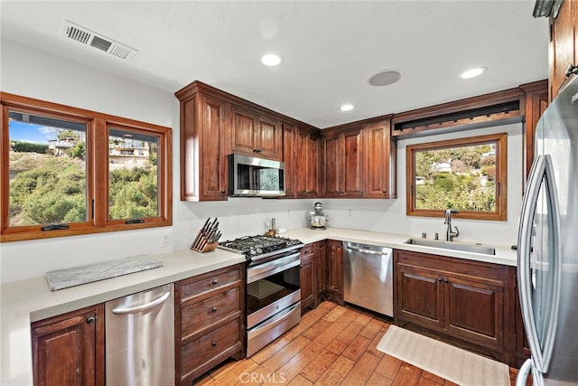 kitchen with stainless steel appliances, sink, and light wood-type flooring