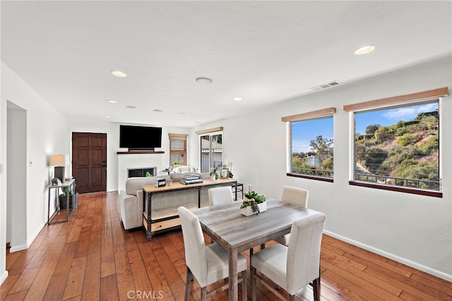 dining room featuring dark wood-type flooring and a brick fireplace