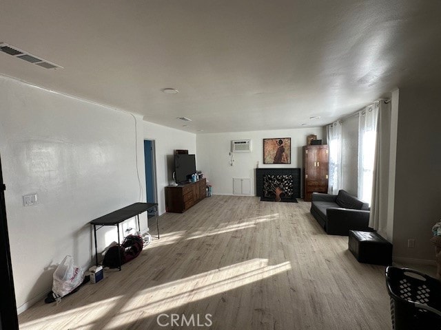 living room featuring a wall unit AC and light hardwood / wood-style floors