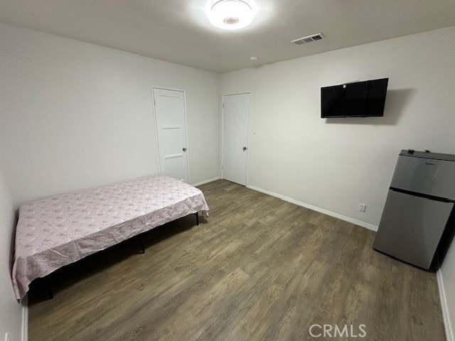 bedroom featuring stainless steel refrigerator and dark wood-type flooring