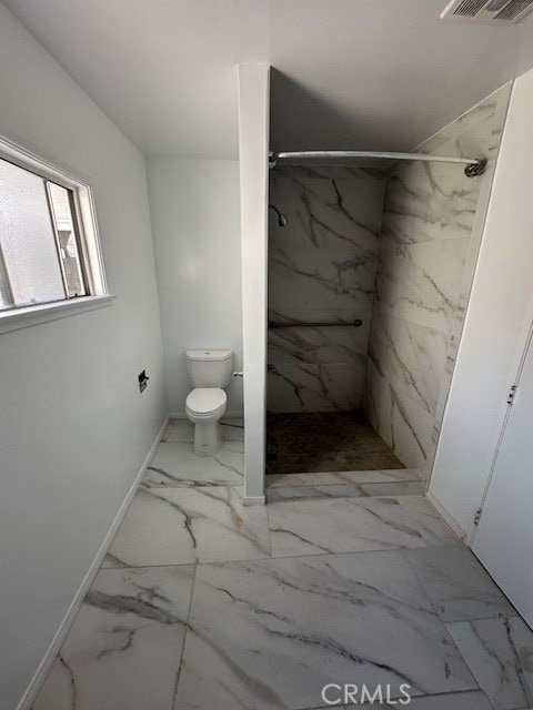 bathroom with toilet and tiled shower