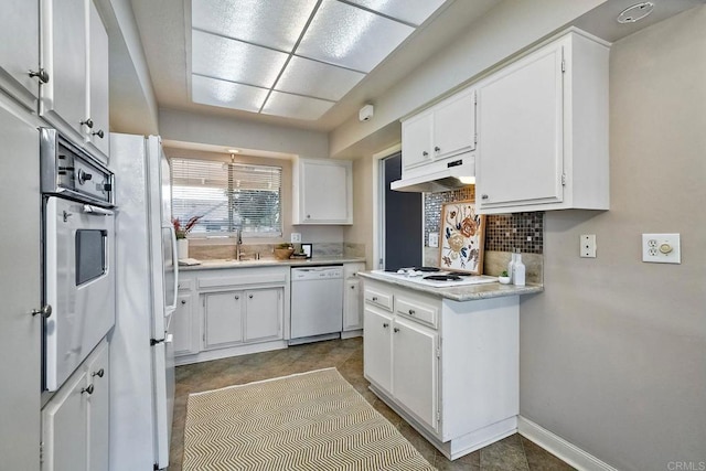 kitchen with backsplash, white appliances, sink, and white cabinets