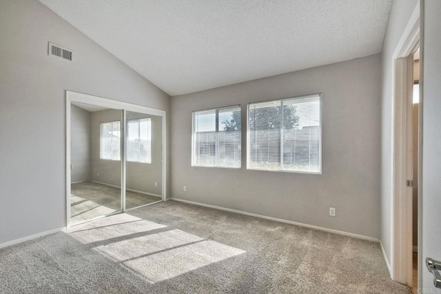 unfurnished bedroom featuring vaulted ceiling, light carpet, a closet, and a textured ceiling