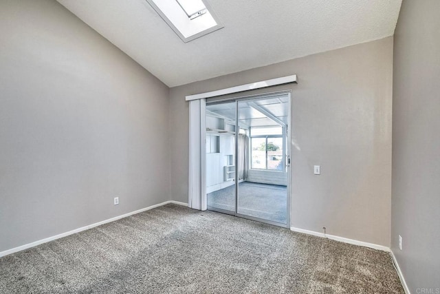 empty room with vaulted ceiling with skylight and carpet