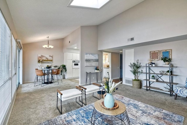 carpeted living room with high vaulted ceiling, an inviting chandelier, and a skylight