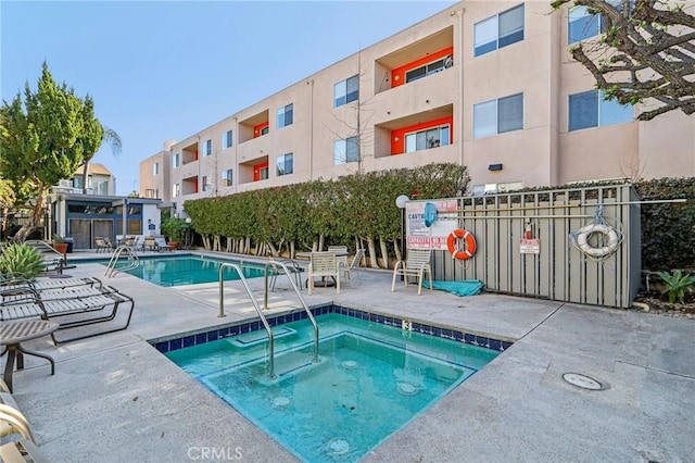 view of swimming pool featuring a hot tub and a patio