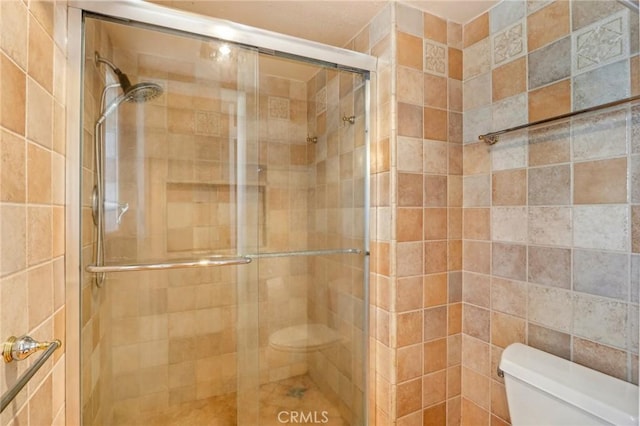 bathroom featuring toilet and a shower with door