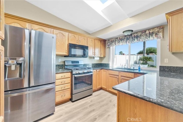 kitchen featuring lofted ceiling, dark stone countertops, kitchen peninsula, stainless steel appliances, and light hardwood / wood-style floors