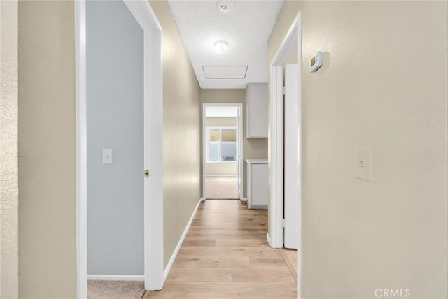 hall with light hardwood / wood-style flooring and a textured ceiling