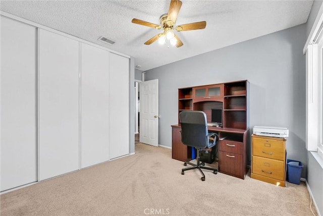 carpeted home office with a textured ceiling and ceiling fan