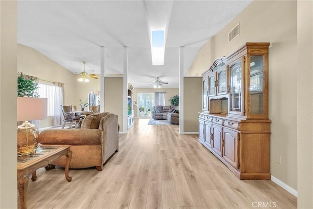 living room with plenty of natural light, lofted ceiling with skylight, and light wood-type flooring