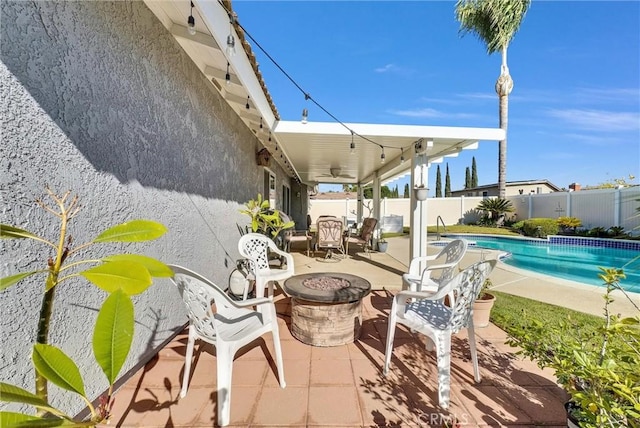 view of patio featuring a fenced in pool, ceiling fan, and an outdoor fire pit