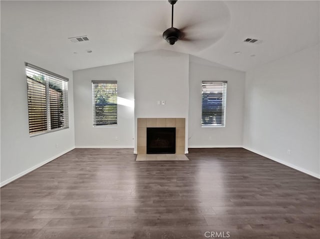 unfurnished living room featuring a tiled fireplace, vaulted ceiling, dark hardwood / wood-style floors, and ceiling fan