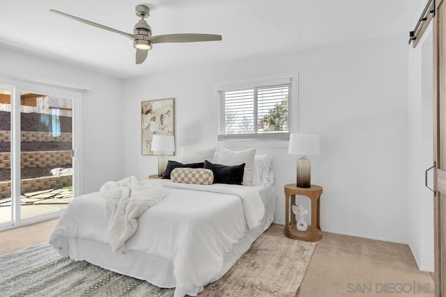 bedroom featuring light carpet, access to exterior, a barn door, and ceiling fan