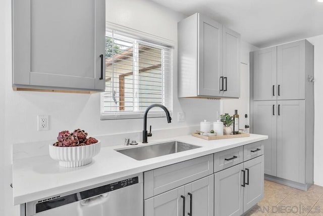 kitchen featuring light tile patterned floors, dishwasher, sink, and gray cabinetry