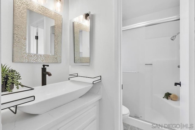 bathroom featuring a shower with door, vanity, and toilet