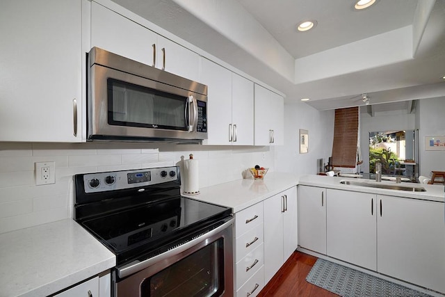 kitchen featuring sink, appliances with stainless steel finishes, white cabinetry, tasteful backsplash, and dark hardwood / wood-style flooring