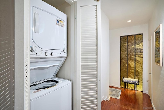 laundry room with stacked washing maching and dryer and hardwood / wood-style floors