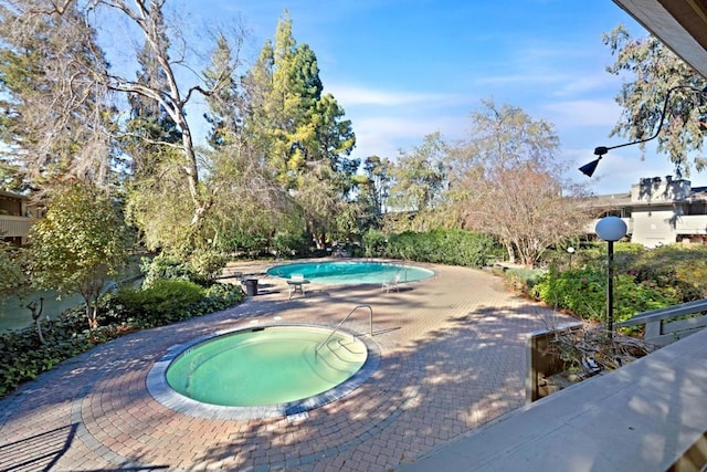 view of pool featuring a patio area and an in ground hot tub