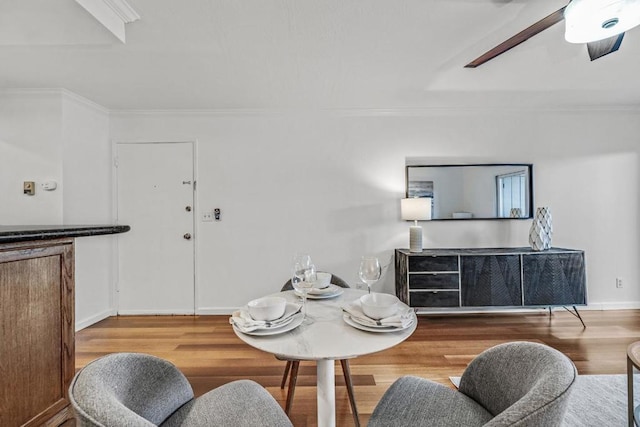 dining space with crown molding, ceiling fan, and wood-type flooring