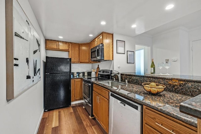 kitchen with stainless steel appliances, sink, dark wood-type flooring, and dark stone counters