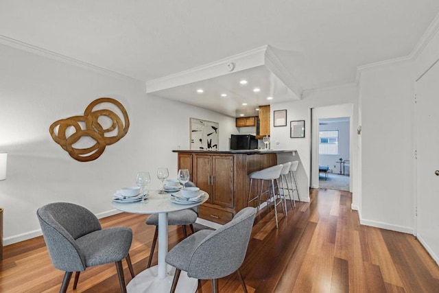 dining space with ornamental molding and light hardwood / wood-style floors