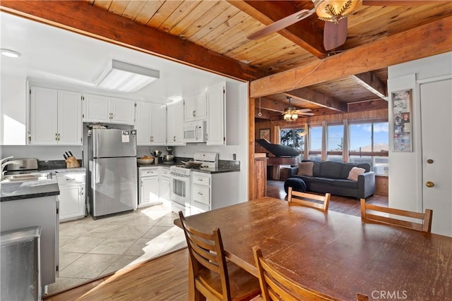 interior space with beamed ceiling, white appliances, sink, and white cabinets