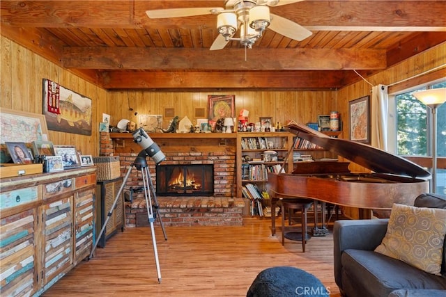 sitting room featuring a brick fireplace, wooden ceiling, wooden walls, beamed ceiling, and light hardwood / wood-style floors