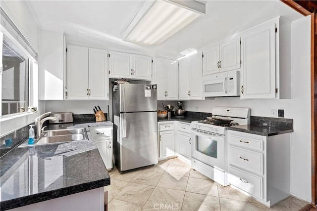 kitchen featuring white cabinetry, sink, dark stone countertops, and white appliances