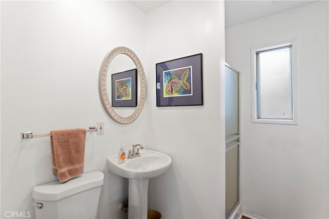 bathroom featuring a shower with shower door and toilet