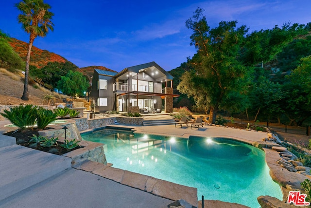 pool at dusk with a mountain view and a patio