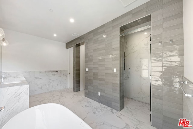 bathroom featuring tile walls, vanity, and plus walk in shower