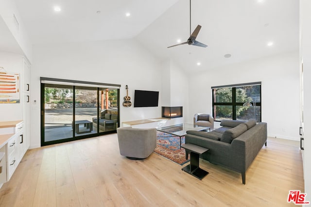 living room featuring high vaulted ceiling, ceiling fan, and light wood-type flooring