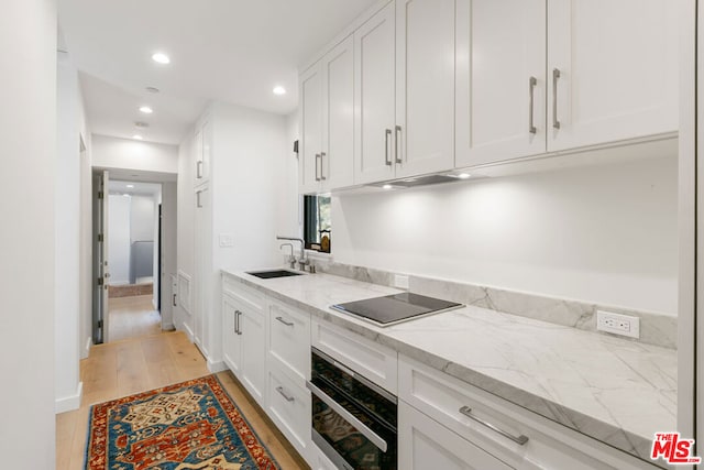 kitchen with sink, light hardwood / wood-style flooring, black electric stovetop, white cabinets, and stainless steel oven