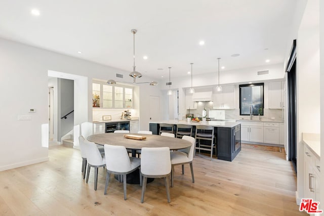 dining room featuring sink, wine cooler, and light hardwood / wood-style floors