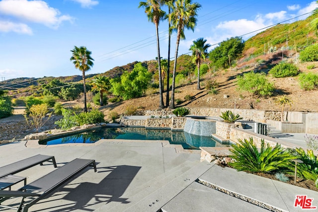 view of pool featuring an in ground hot tub, a mountain view, and a patio area