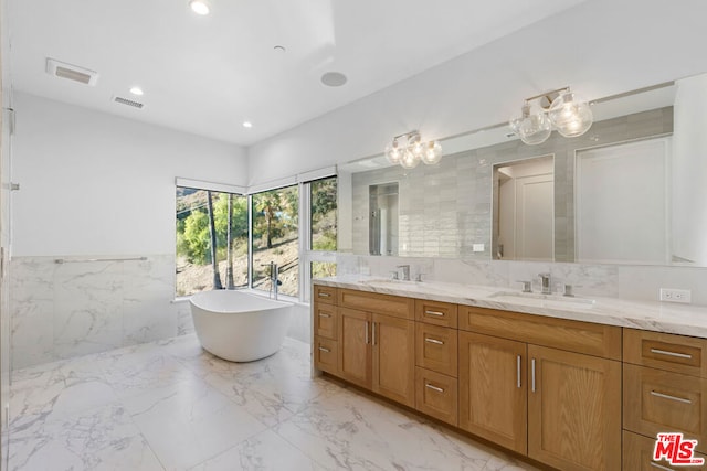 bathroom featuring vanity, a tub to relax in, and tile walls