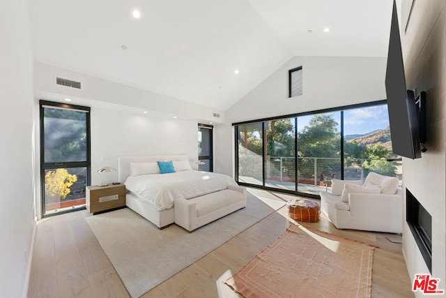 bedroom with high vaulted ceiling and light wood-type flooring