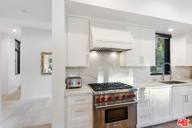 kitchen with custom range hood, sink, designer stove, and white cabinets