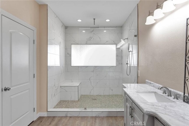 bathroom with hardwood / wood-style floors, vanity, and a tile shower