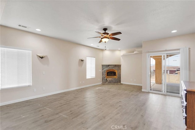 unfurnished living room featuring ceiling fan, light wood-type flooring, and a fireplace