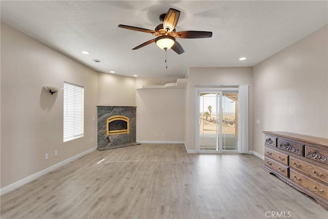 unfurnished living room with a premium fireplace, ceiling fan, and light hardwood / wood-style floors