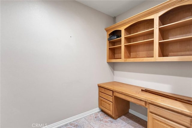 unfurnished office featuring built in desk and light tile patterned floors