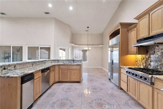 kitchen featuring stainless steel appliances, pendant lighting, light brown cabinets, and light stone counters