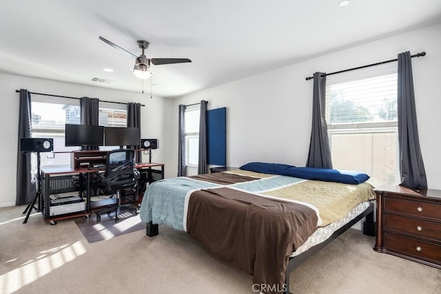 carpeted bedroom featuring multiple windows and ceiling fan