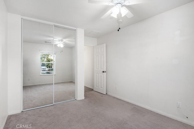 unfurnished bedroom featuring light colored carpet, a closet, and ceiling fan