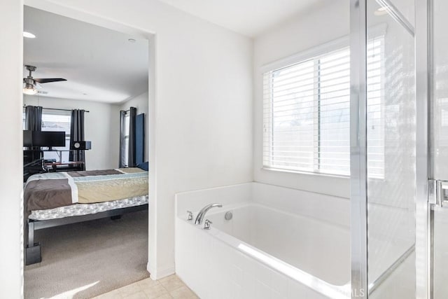 bathroom featuring tiled bath and ceiling fan