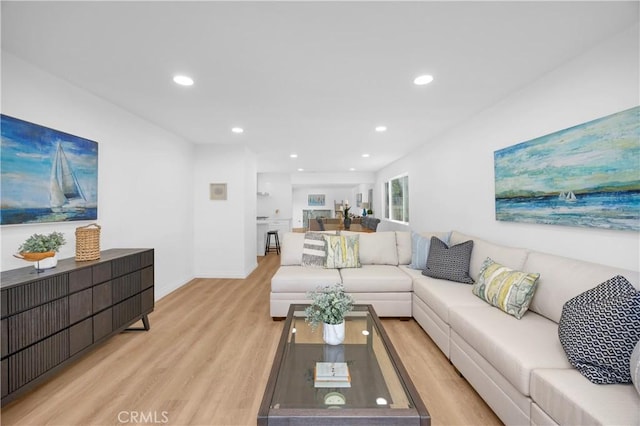 living room featuring recessed lighting, baseboards, and light wood finished floors